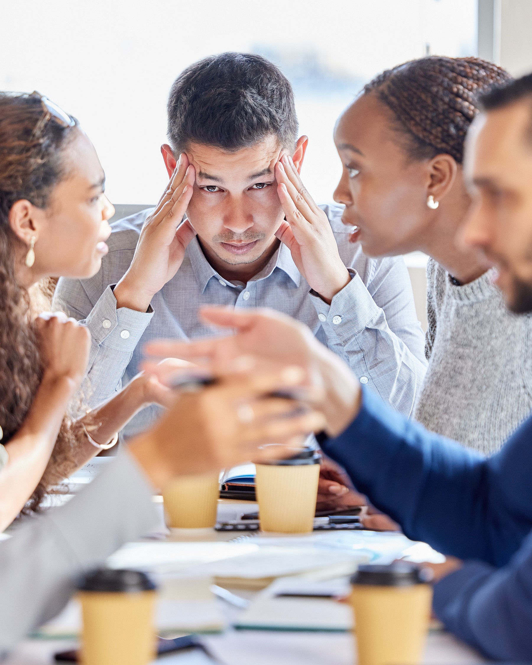 Shot of a young businessman looking stressed out in a meeting at work Leidinggevende die stress heeft tijdens vergadering